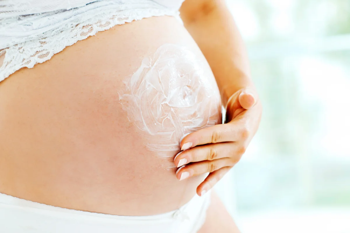 Pregnant woman moisturizing her skin