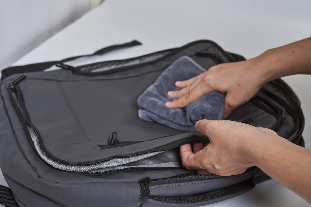 person wiping down outside of backpack with washcloth