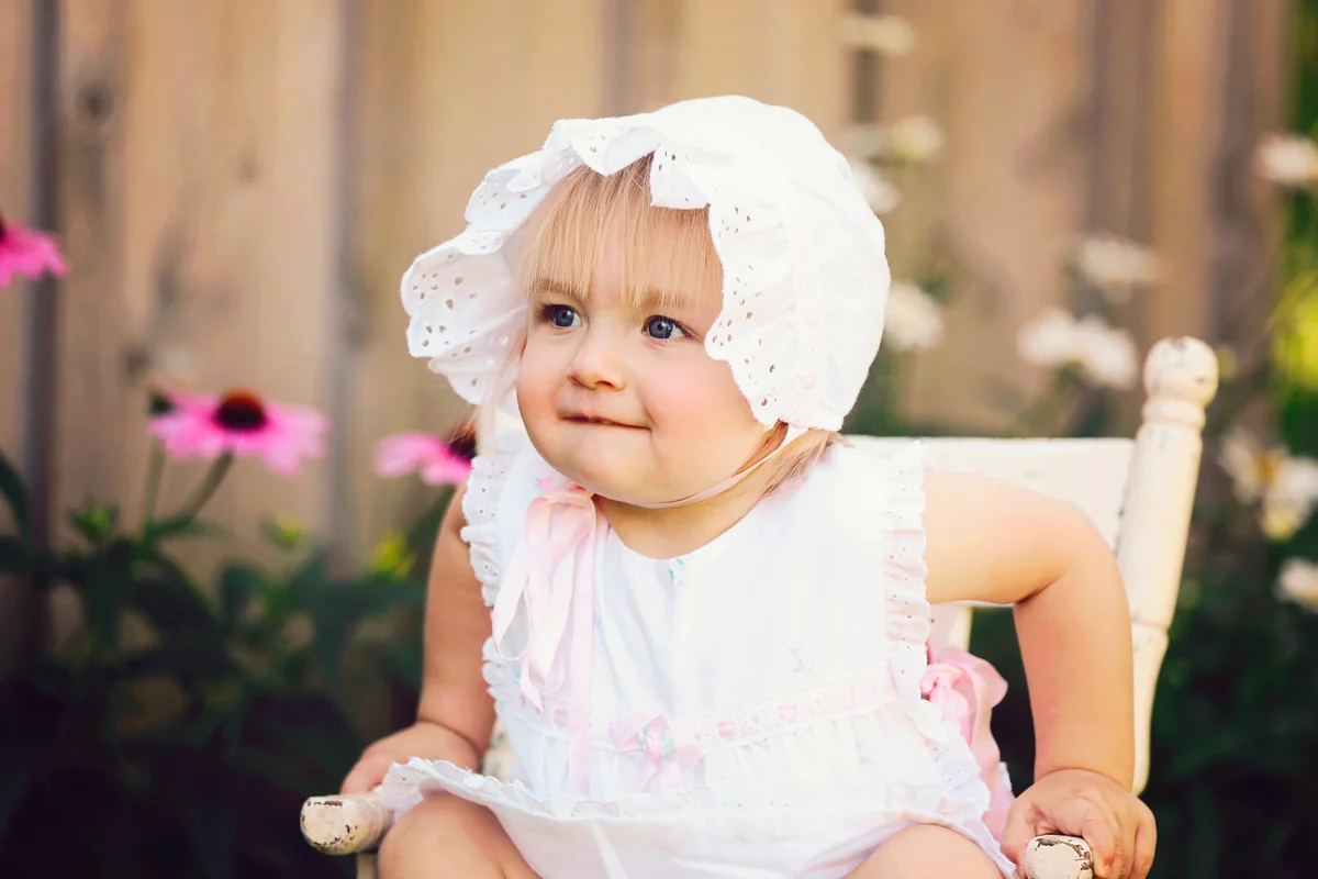 Baby Girl Sitting in Old Wooden Chair Wearing Vintage Dress