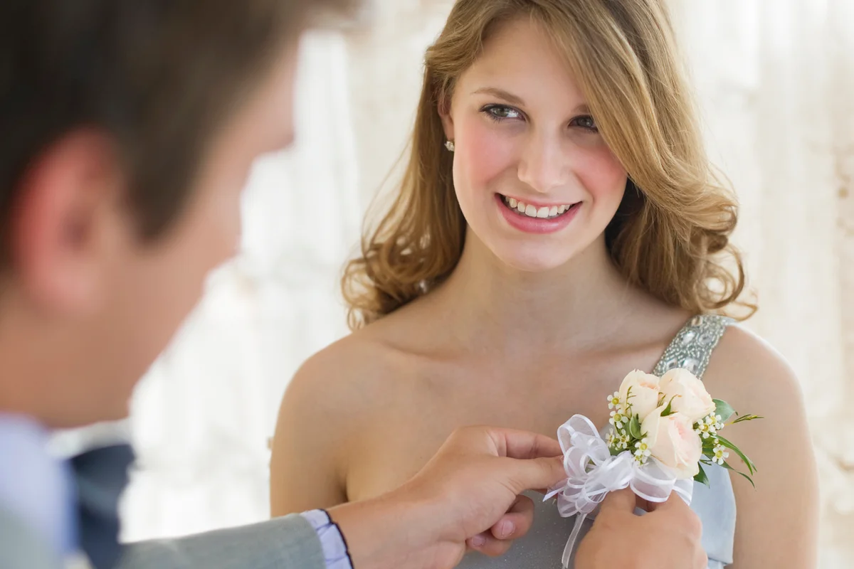 Man pinning corsage on his date's prom dress