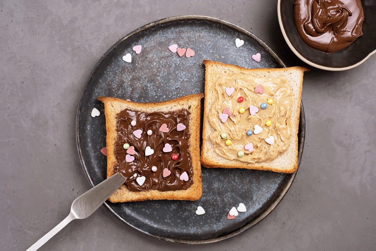 Two toast with Nutella spread and peanut butter sprinkled with colorful hearts