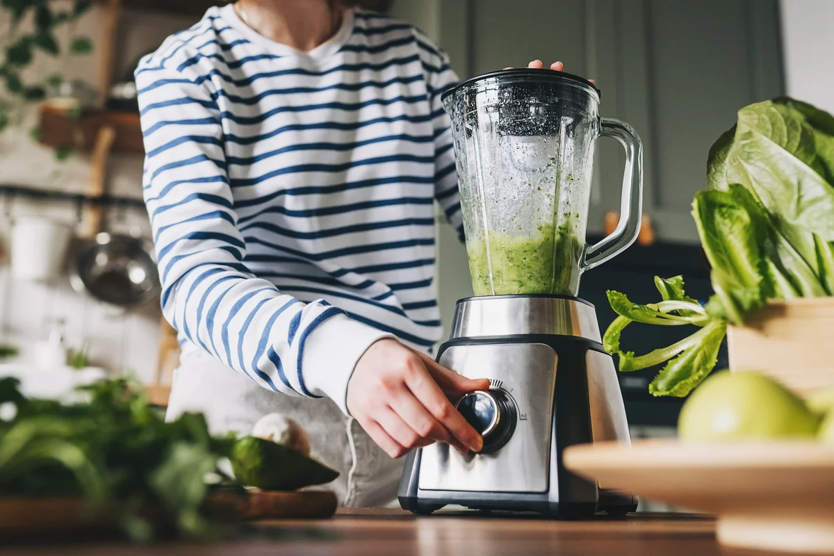 woman blending green food in blender