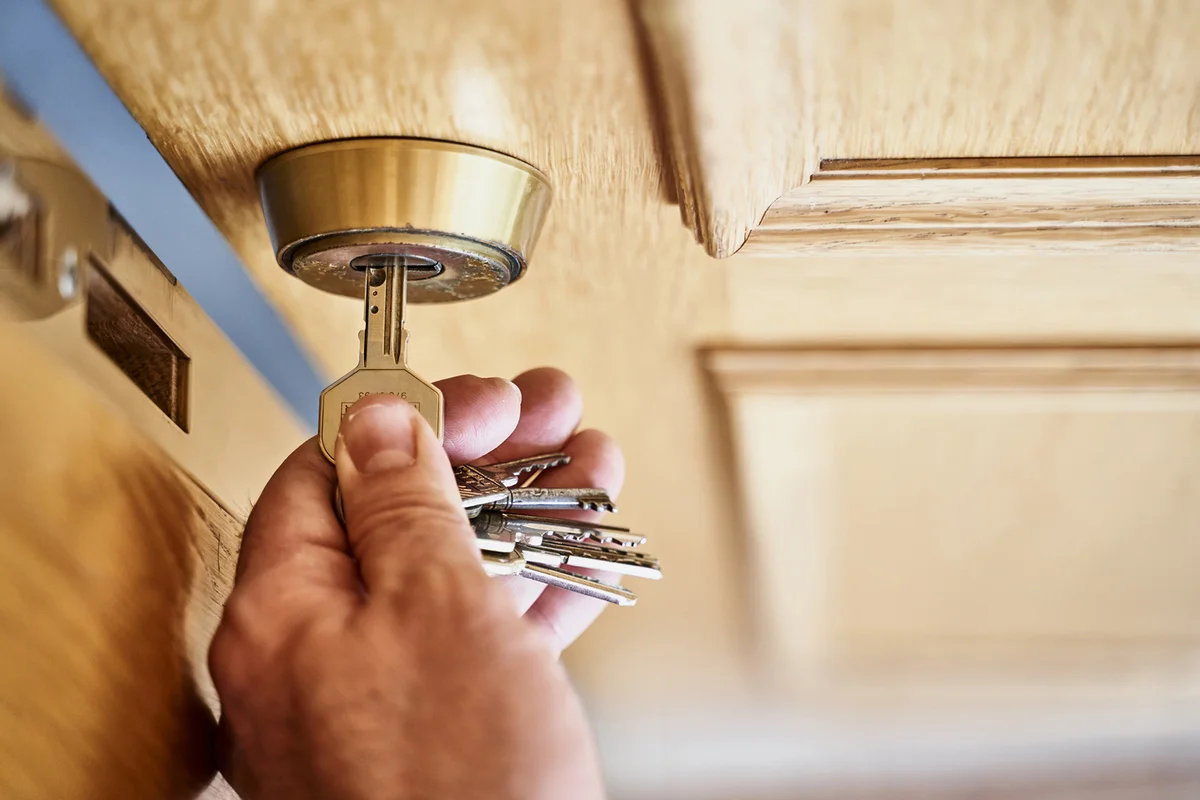 hand with key opening a wooden door