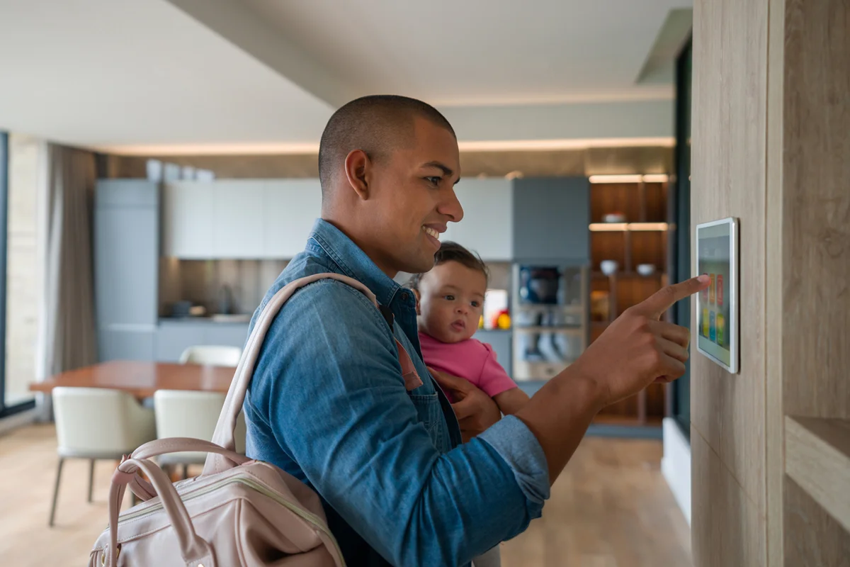 Man leaving the house with his baby and locking the door using a home automation system