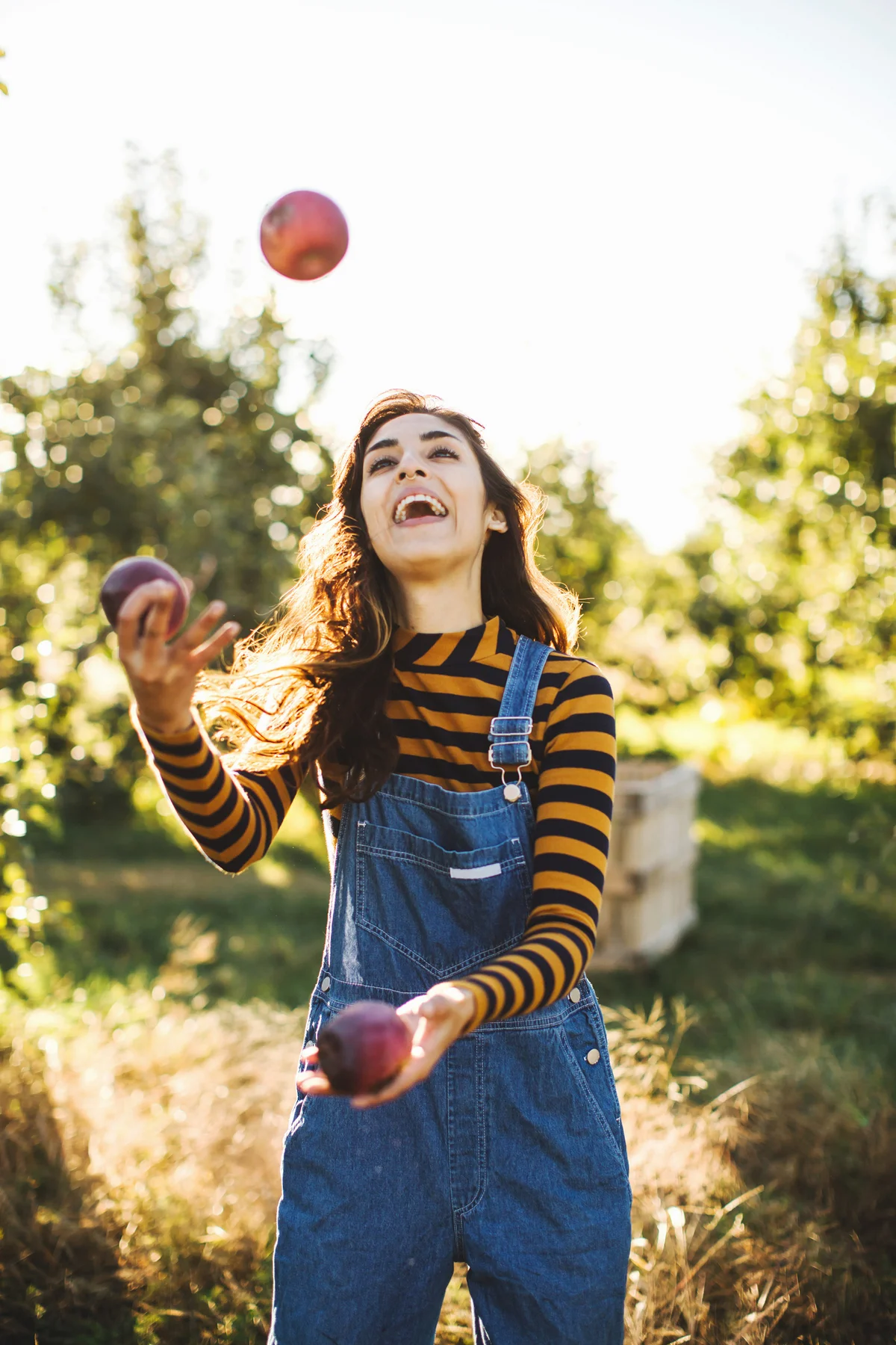 Woman wearing bibs juggling apples in the fall