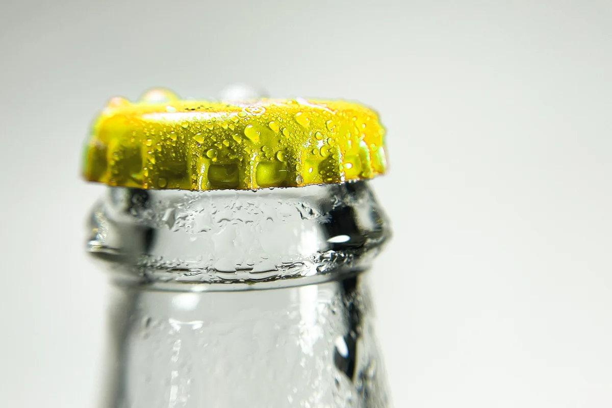 Glass bottle with a yellow cap covered with water droplets