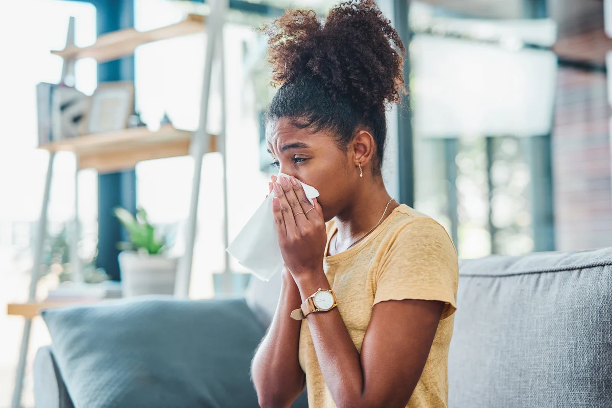 Woman sneezing in her home