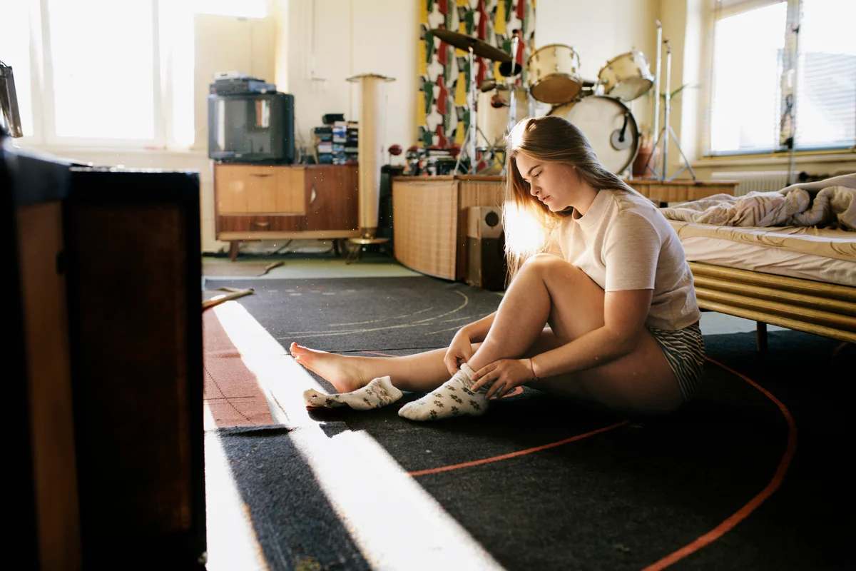 Girl taking off socks at door