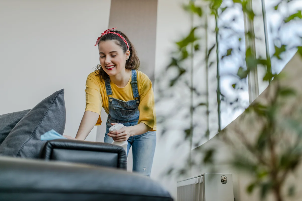 Woman spray couch with anti-allergen spray