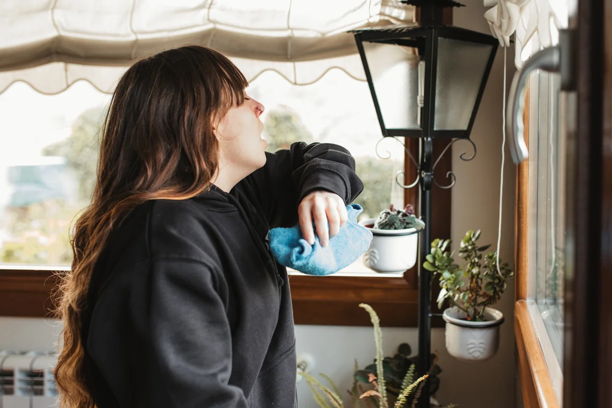Woman sneezing while she cleans.