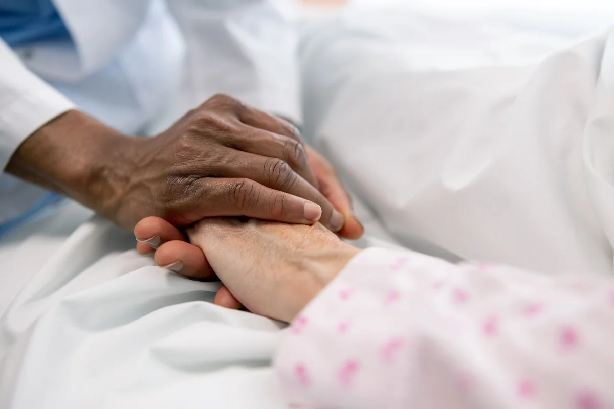 Doctor holding the hand of a sick woman in bed at the hospital