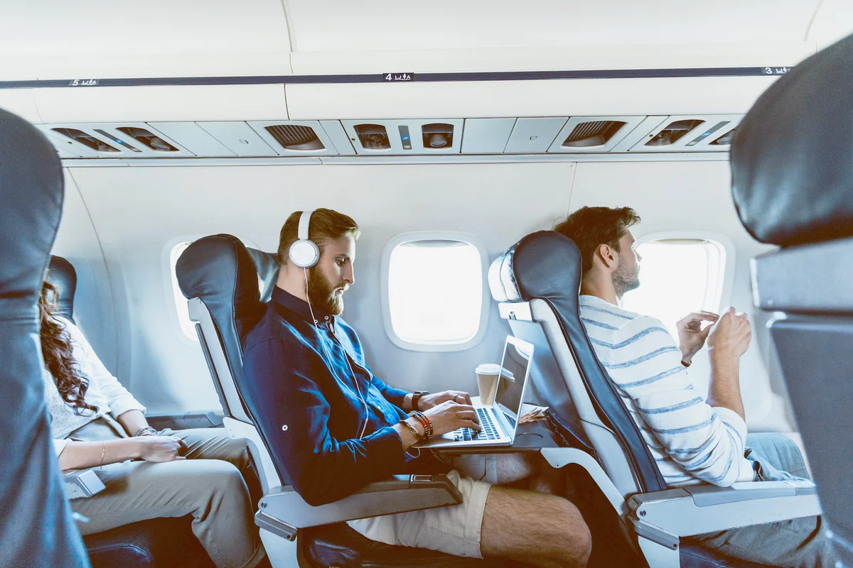 Male passenger using laptop during flight