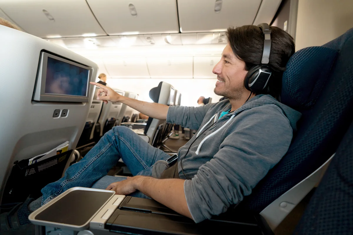 Man traveling by plane and watching onboard entertainment