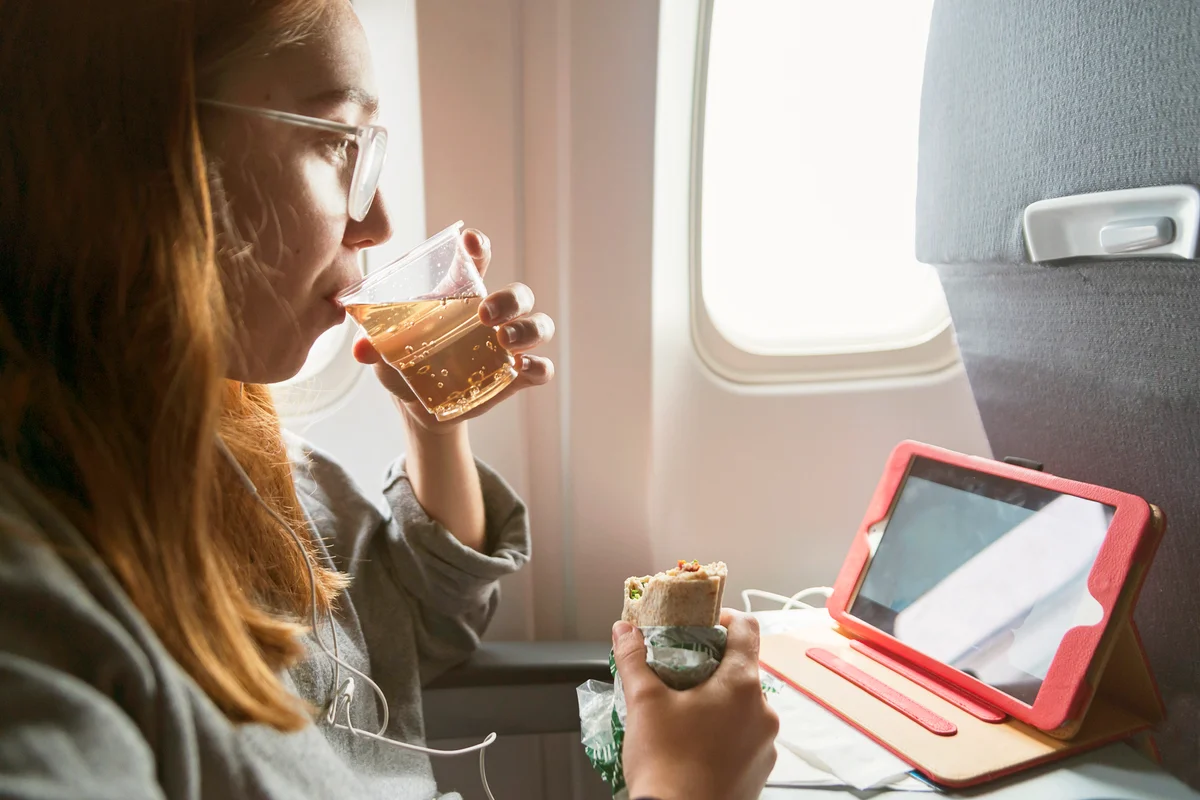 Woman eating and drinking inside an airplane