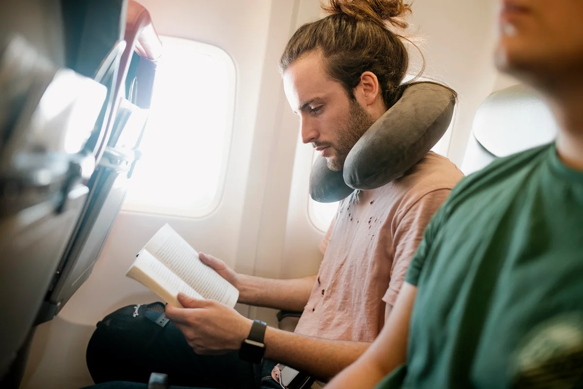 Young man is reading a book while traveling on an airplane