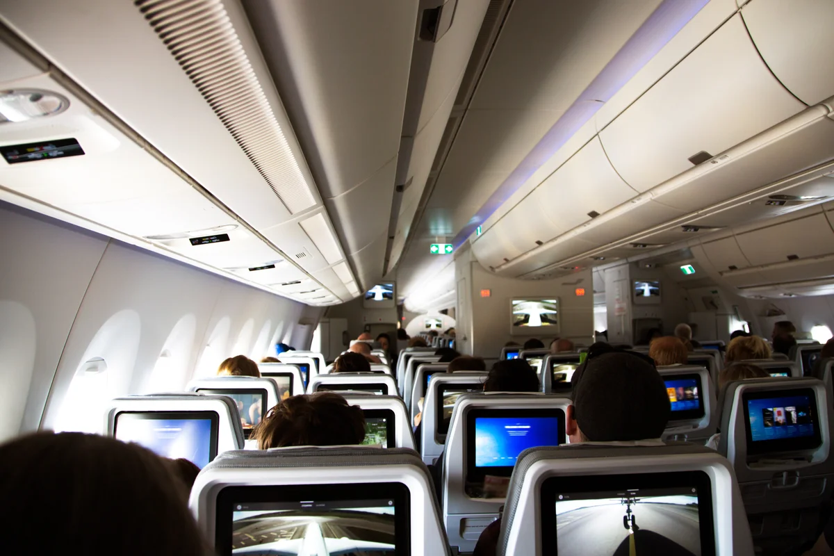Inside of a long distance airplane with passengers sitting and resting during a flight