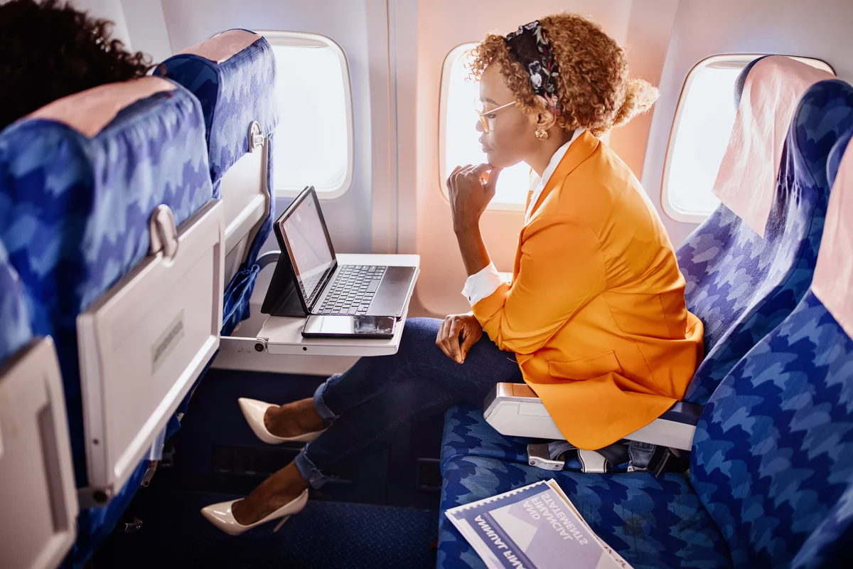 Woman working on laptop sitting near window in an airplane