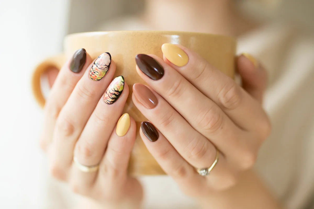 Hands of autumn nails holding a cup of hot tea