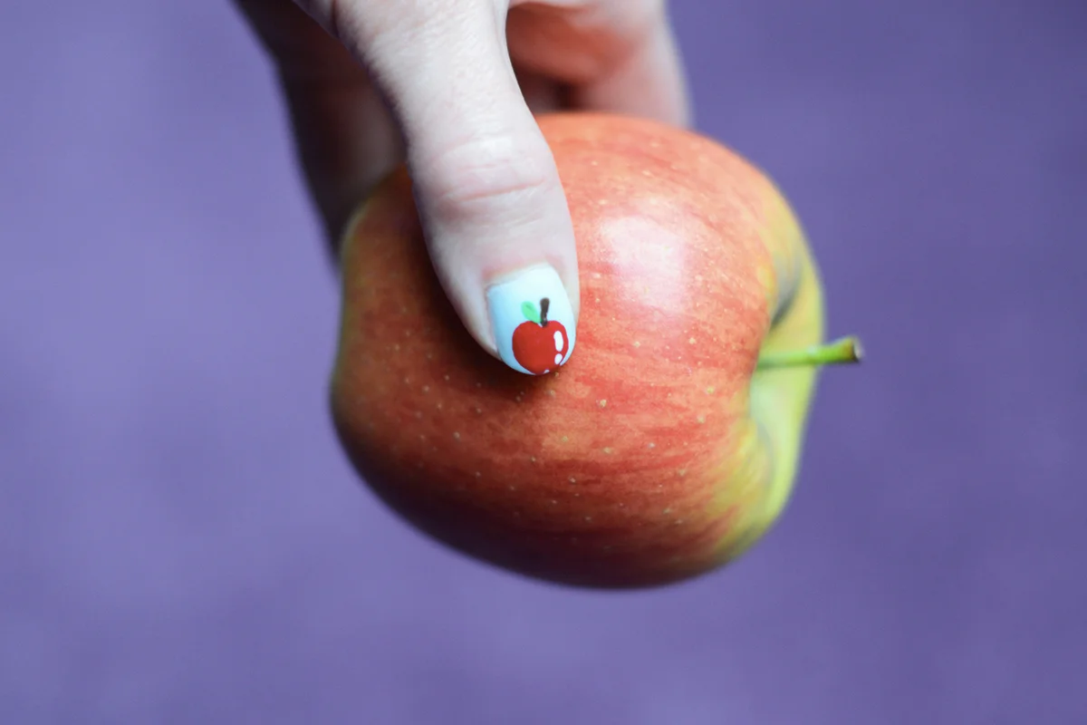 A woman's hand holding a fresh apple