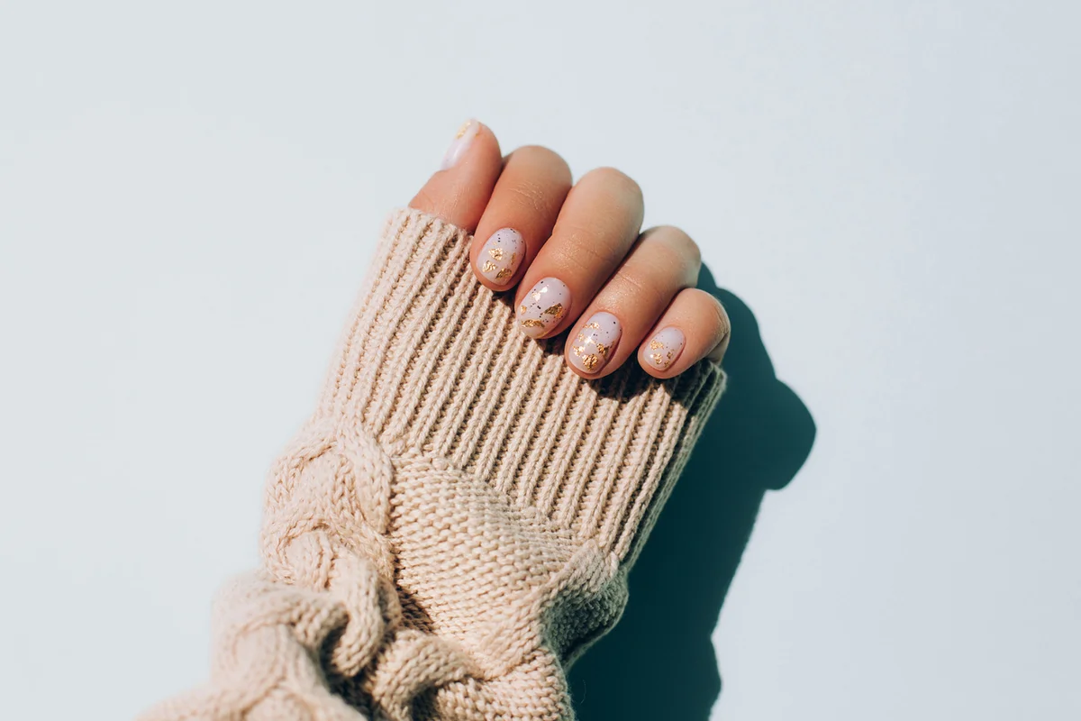 Woman's hand in warm sweater showing manicure