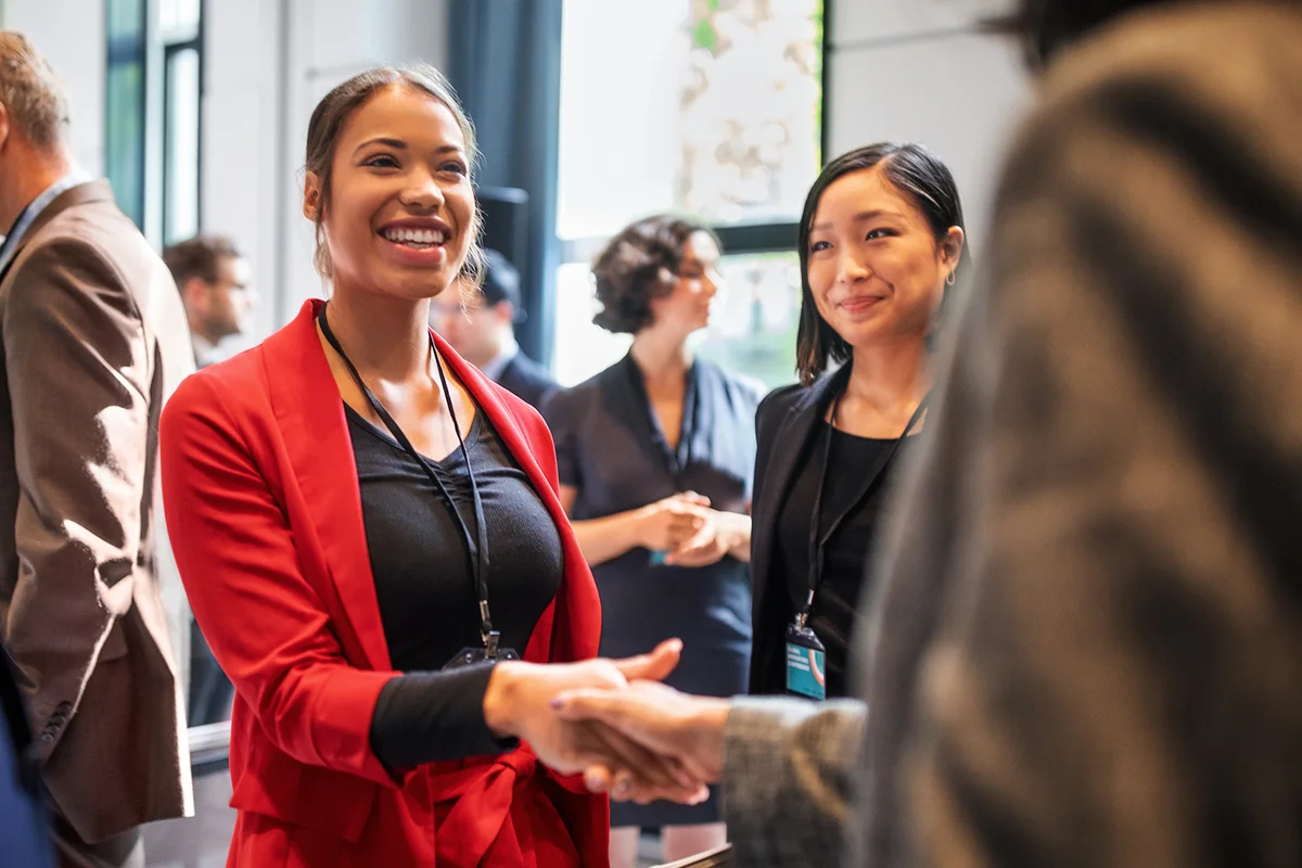 Businesswomen handshaking in auditorium corridor