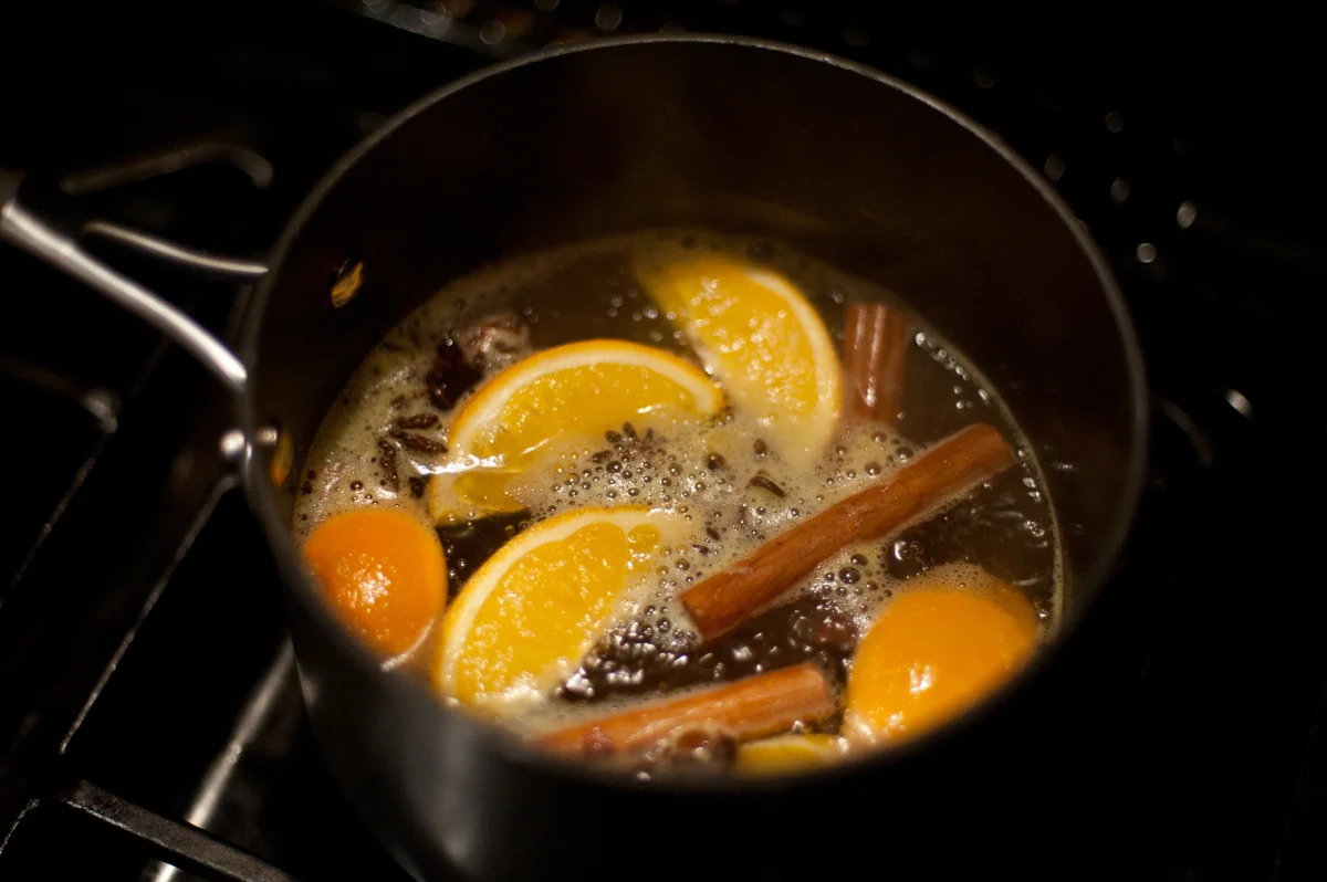 Pot with oranges and cinnamon simmering on stove
