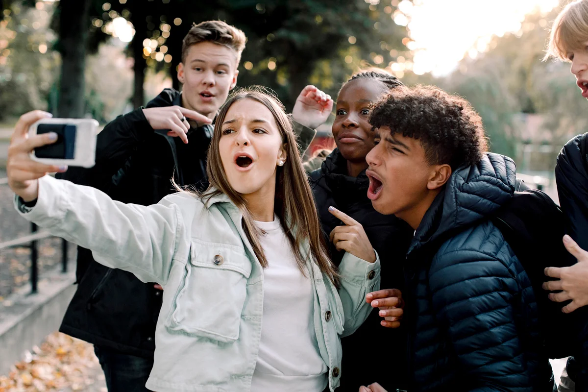 Cheerful teenage friends taking selfie through mobile phone