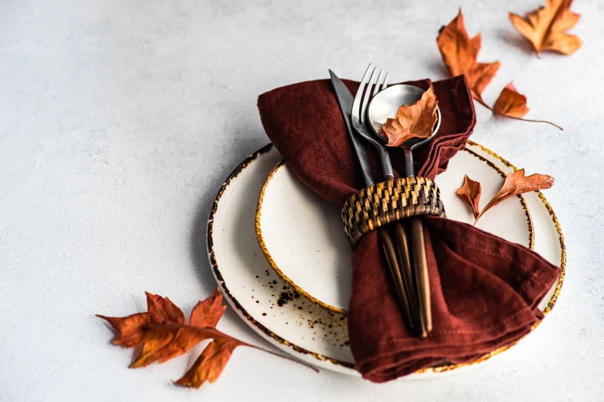 Fall table with brown napkins and brown dried leaves for decor