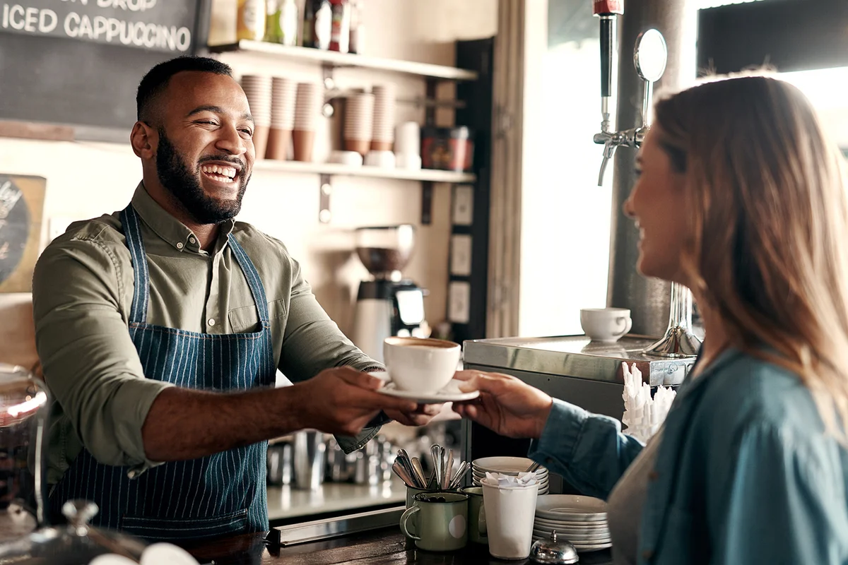 Shot of a young man serving coffee to a customer in a cafe
