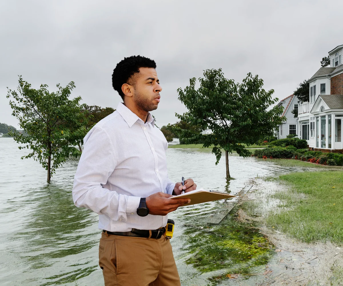 Man looking at flooded houses with clipboard