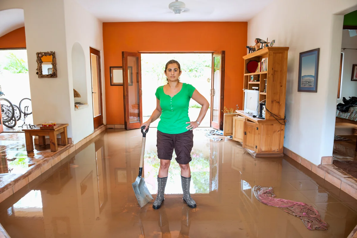 Woman standing in flooded house with shovel