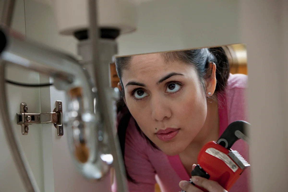 Woman installing backflow valves and looking at pipes