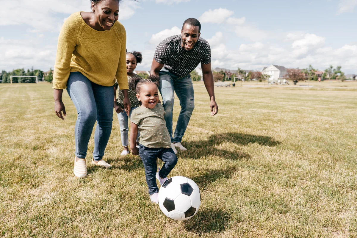 Family playing soccer practice with baby