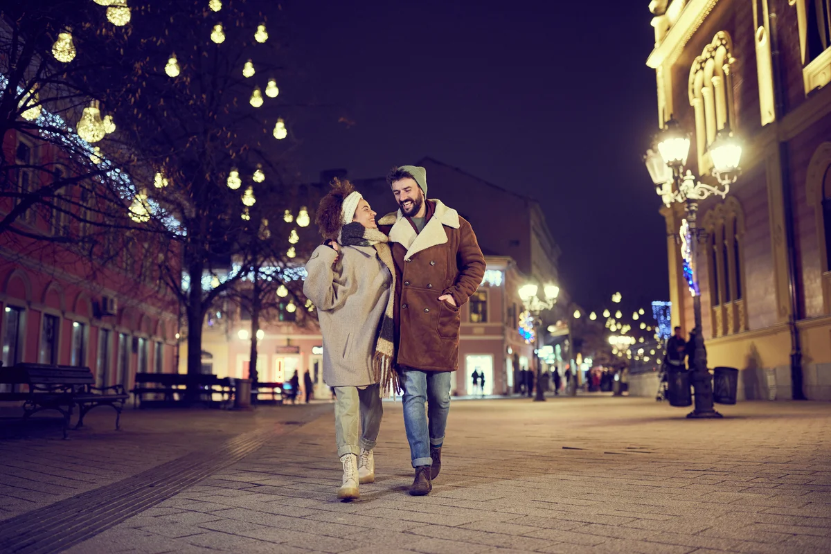 happy couple walking through city on winter night