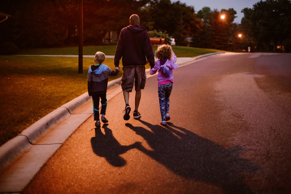 Father walking with two kids at night