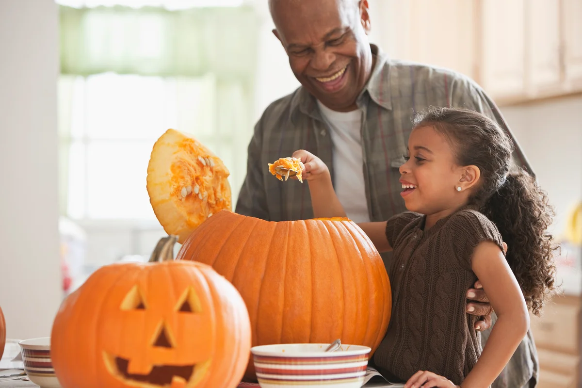 Grandpa and granddaughter carving pumpkins