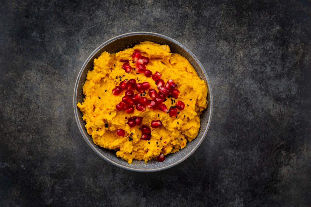 Bowl of pumpkin hummus garnished with pomegranate