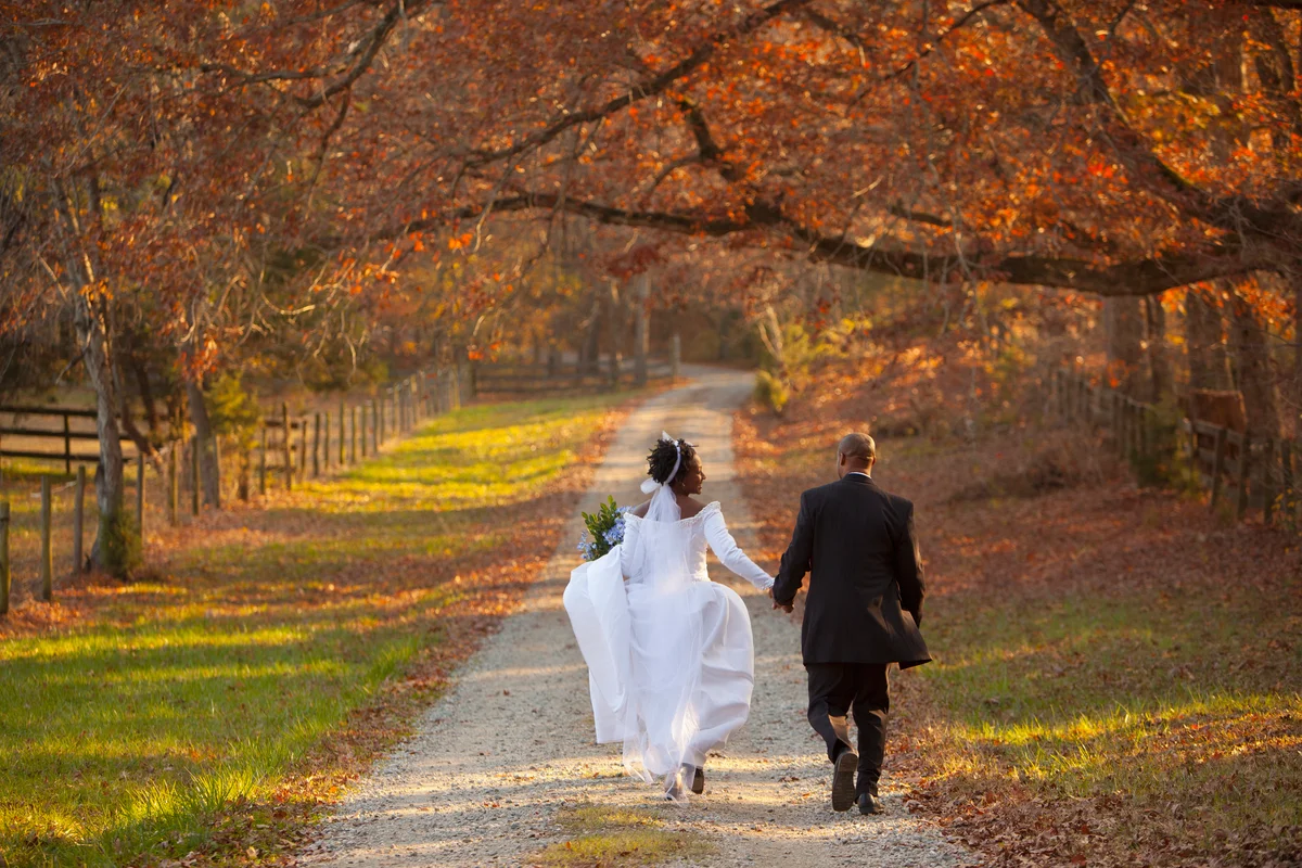 Wedding couple running down autumn path