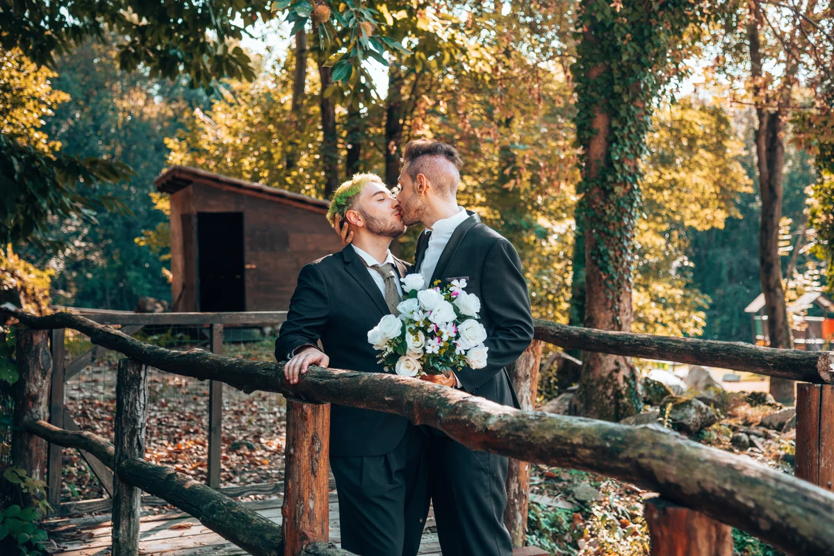 Two men on their wedding day kissing in a beautiful outdoor fall setting
