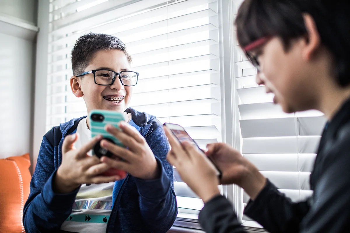 School age boys playing with smartphones