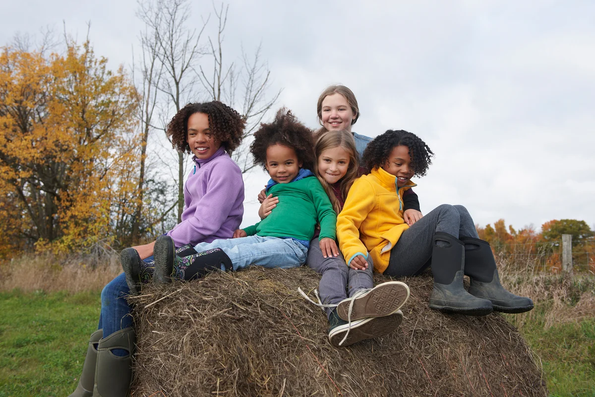 Children playing on hay bale in field