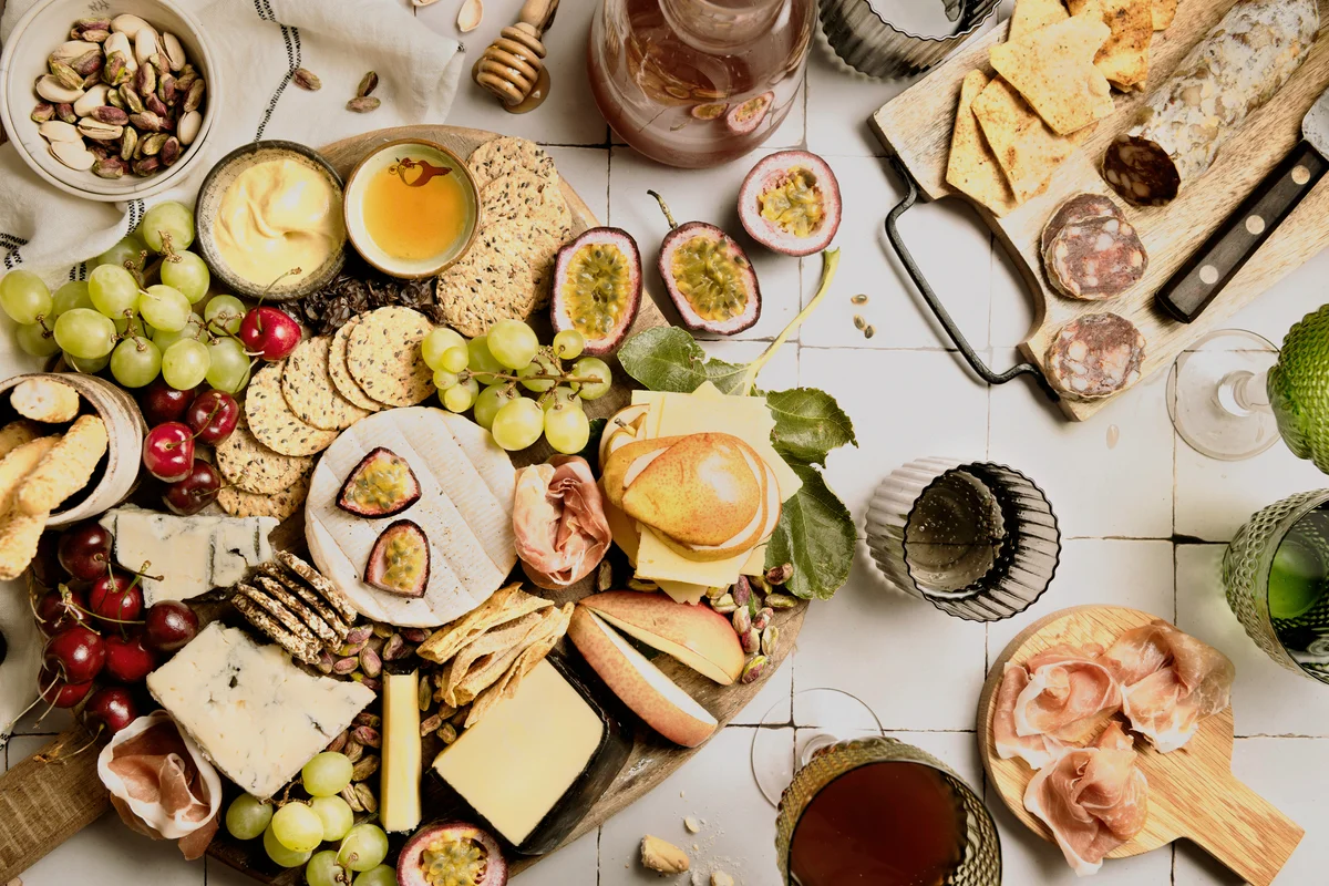 Top down wide angle view of mixed cheese, charcuterie and fruits, with wine