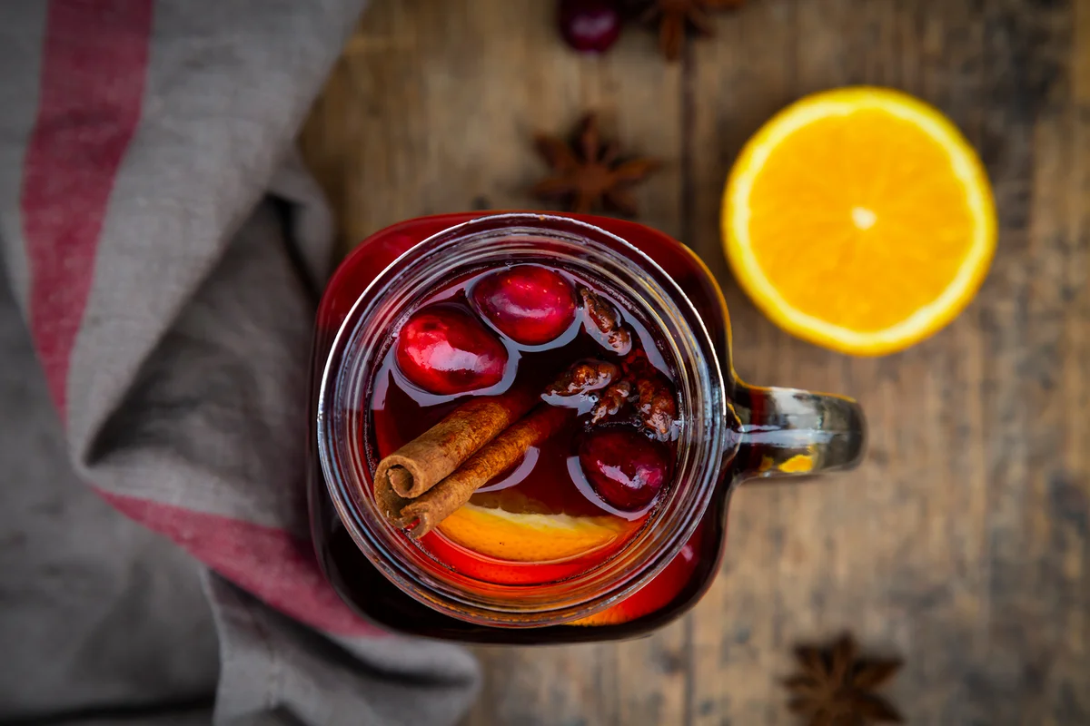 Glass of mulled wine with cranberries, cinnamon sticks, orange and star anise
