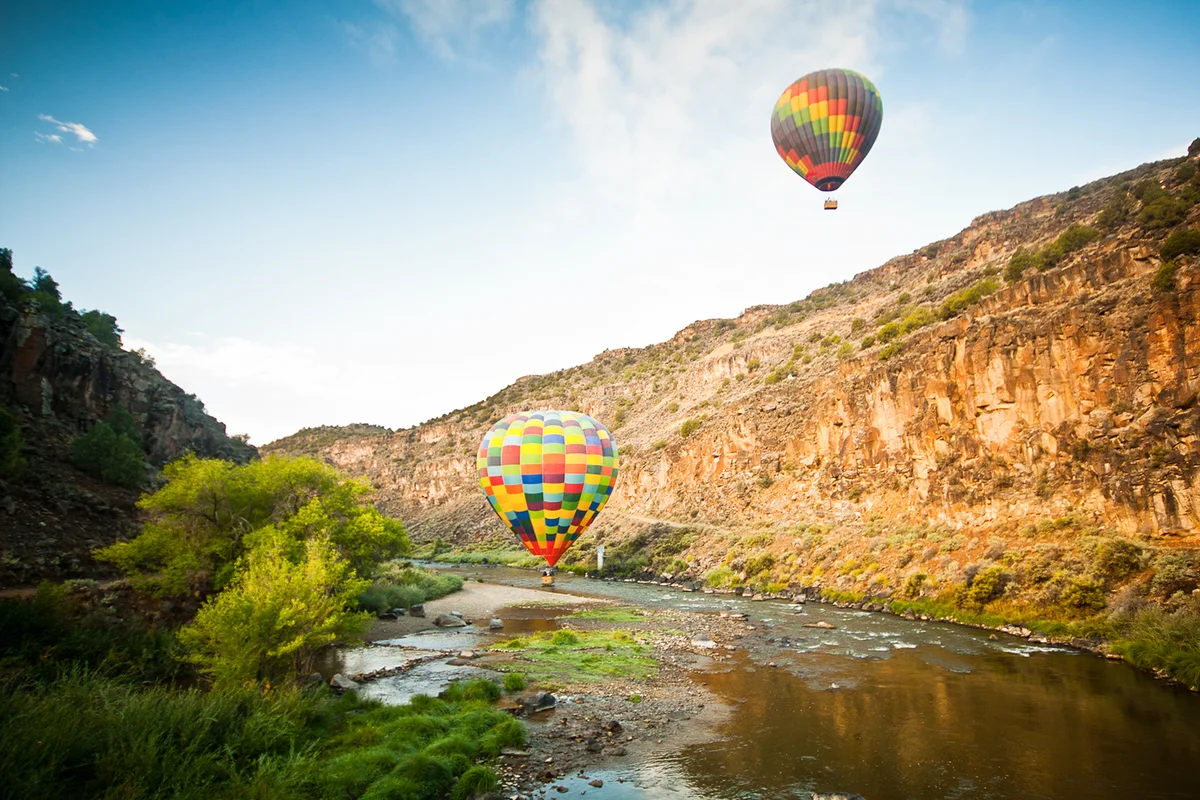 Two multi-colored hot air balloons coming in for water landing on Rio Grande river in new Mexico