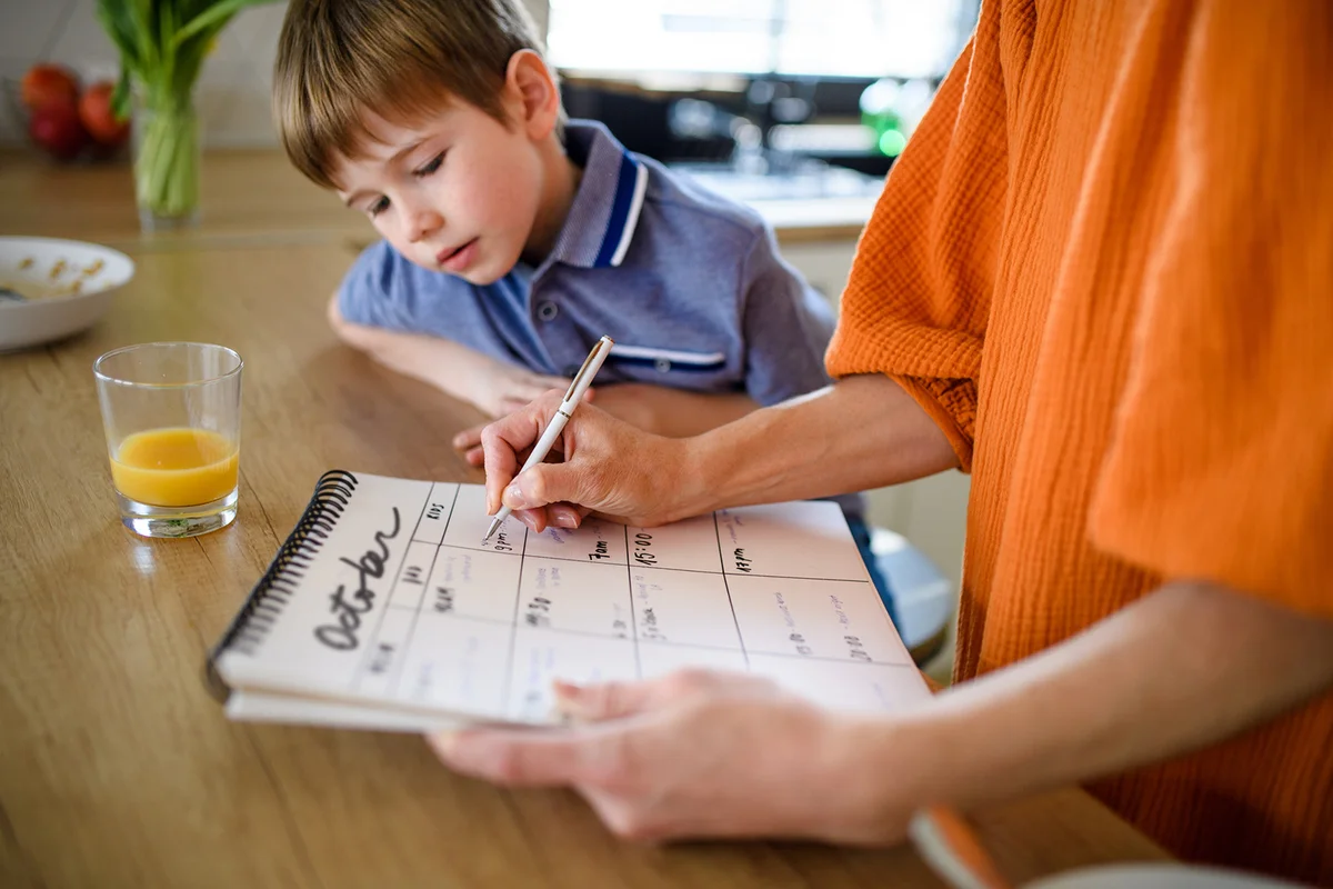 Woman with son making notes in personal organizer.