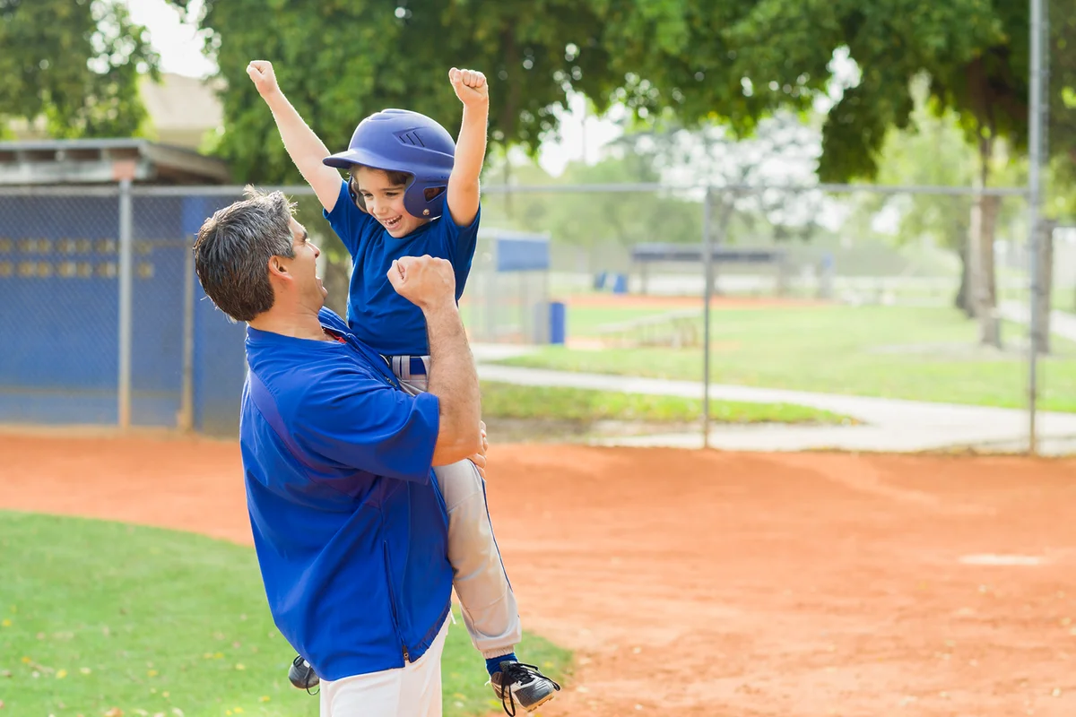 Coach and young baseball player cheering