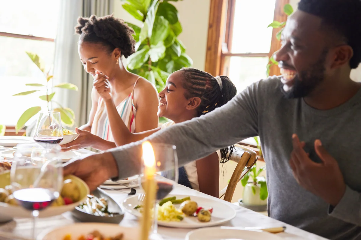 Family laughing during dinner together around a table at home