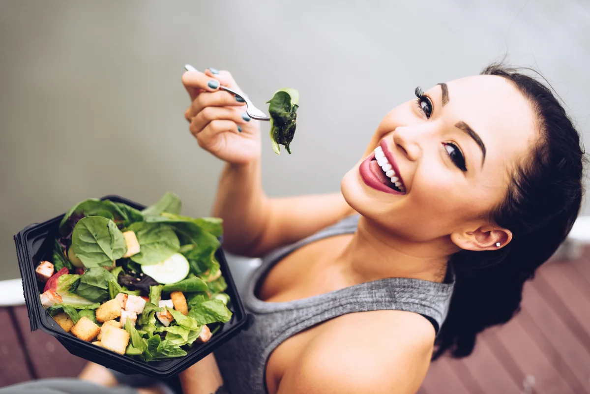 woman eating salad and smiling