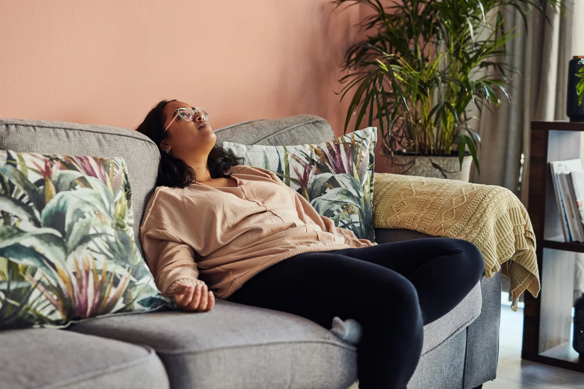 Woman laying on couch looking bummed