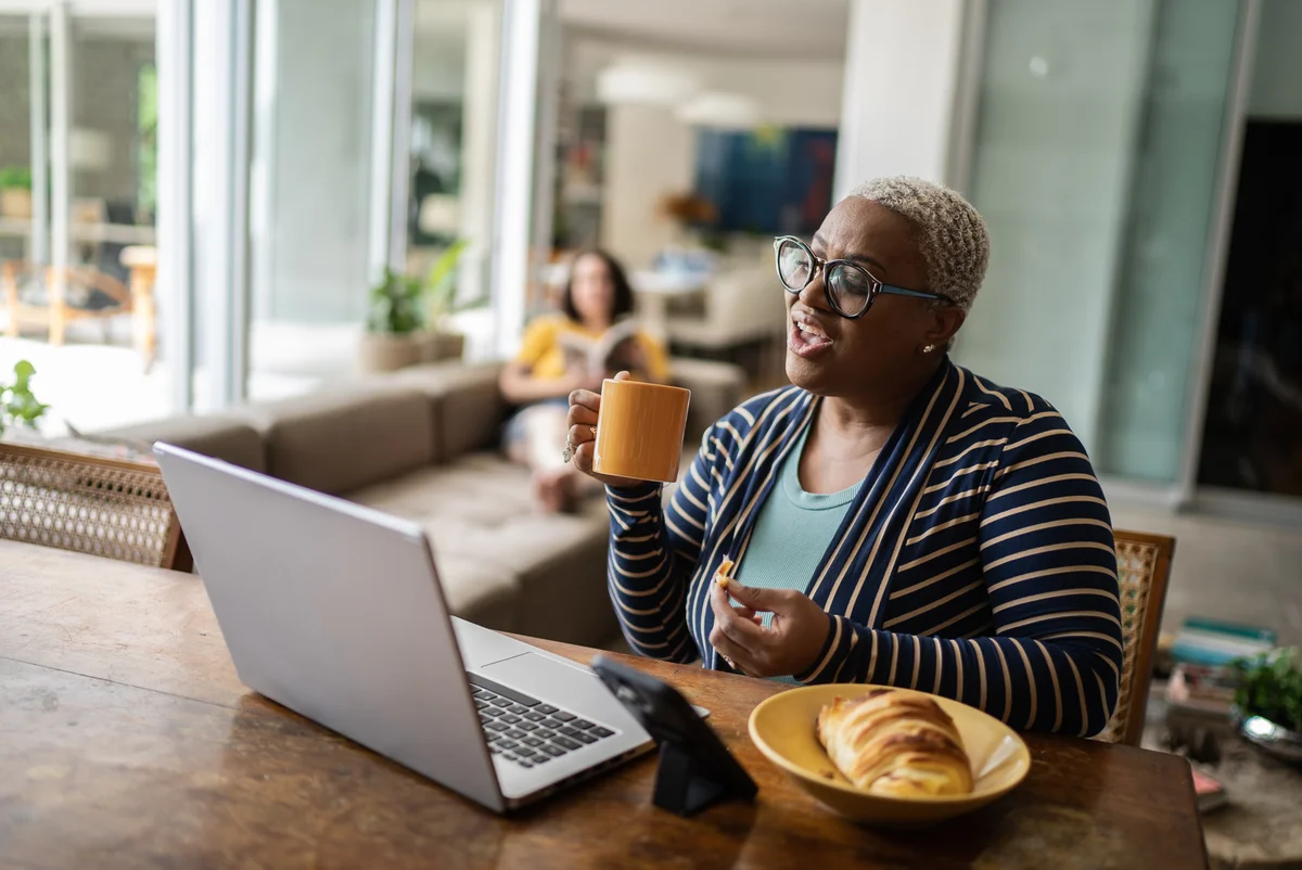 Woman talking on laptop with coffee and a pastry